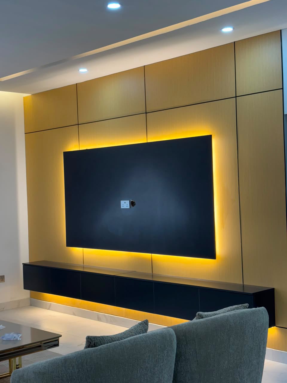 Close view of black floating TV console and warm backlit panel